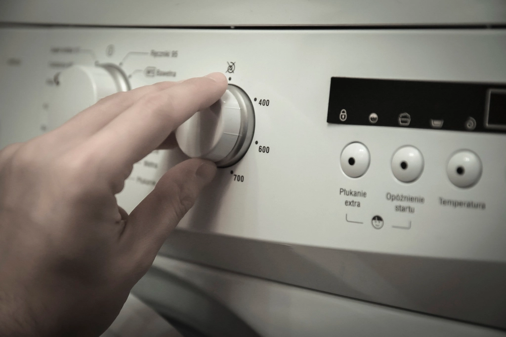 A hand turning the dial on a washing machine